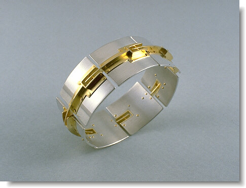 A silver and gold bracelet with rivets.