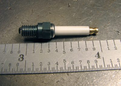 A spark plug for the Ford 300 Inline engine with ruler for reference.