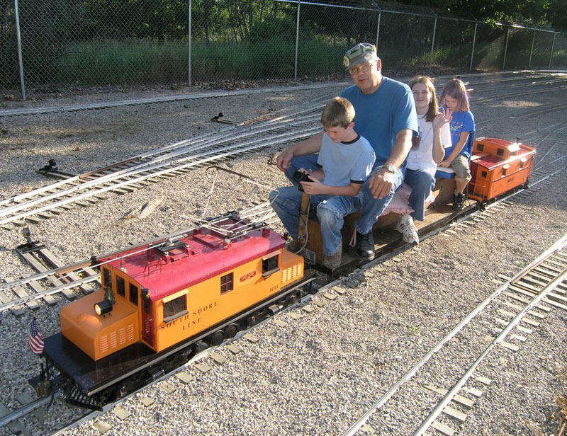 Richard taking his nieces and nephew for a ride on his model locomotive.