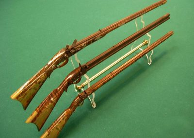 Three finished scale model long rifles.