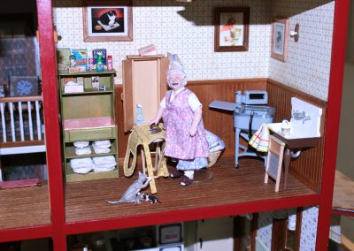 A close-up of the dollhouse laundry room, with porcelain doll.