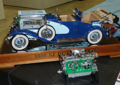 The finished 1/6 scale Duesenberg sits on display with its Liberty V-12 in front.