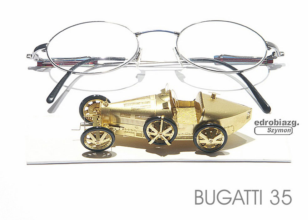 This miniature brass Bugatti is dwarfed by a pair of glasses. 