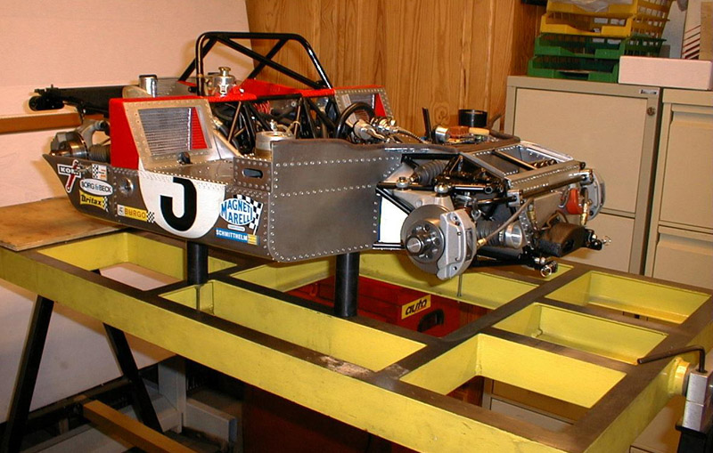 A right side view of the race car with bodywork and wheels removed. 