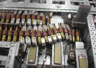 A close-up shows the ammunition belt threading into the open receiver.