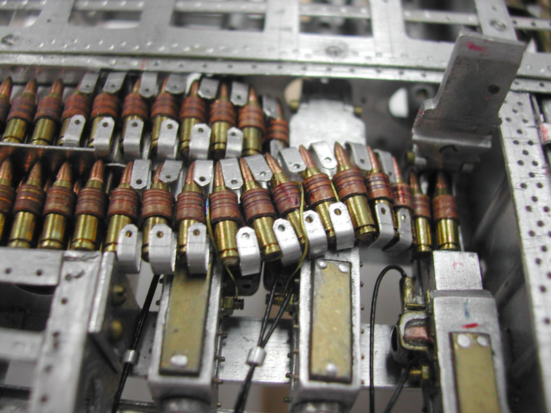 A close-up shows the ammunition belt threading into the open receiver.