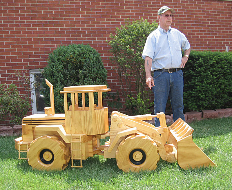 Chuck stands behind his wooden scale model articulated front end loader.