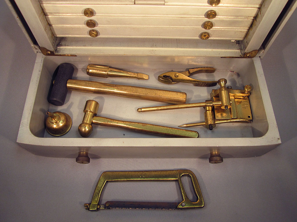 This drawer reveals a miniature hacksaw, hammer, mallet, and other tools.