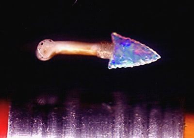 A microscopic knife with an arrowhead style point made from fire opal.
