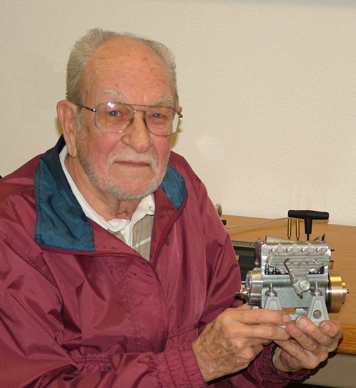 Larry Simon holding the unfinished 4-cylinder Seal engine shop project.