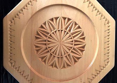 A carved wooden octagon plate with a “circles and points” pattern.