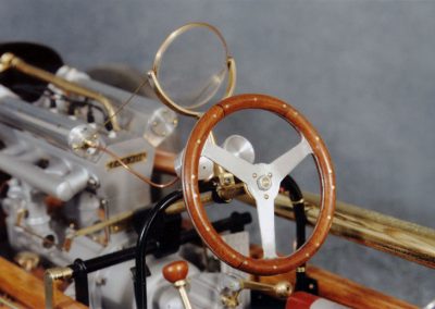 A close-up shows the wooden steering wheel and small glass windshield.