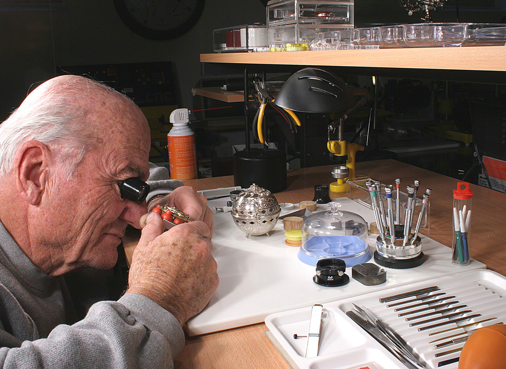 George inspects a watch assembly on the bench. 