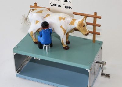 This animated, hand-cranked toy features a farmer milking a cow.