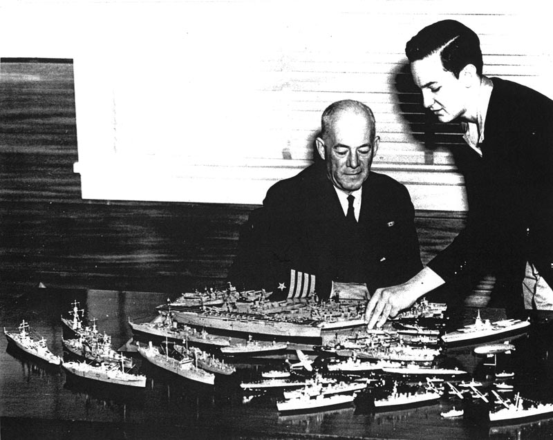 Seventeen-year-old Bill Tompkins (right) points out some details on his models to Navy Captain H.C. Gearing.