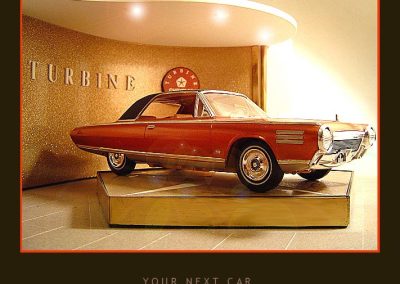 A 1963 Chrysler Turbine sits on a turntable in an ultra-modern showroom.