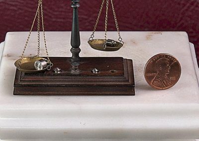 A miniature balance scale with a US penny for size comparison.