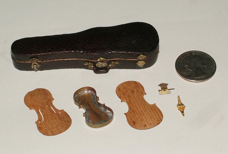 A miniature violin and bow in a fitted case, along with spare parts.