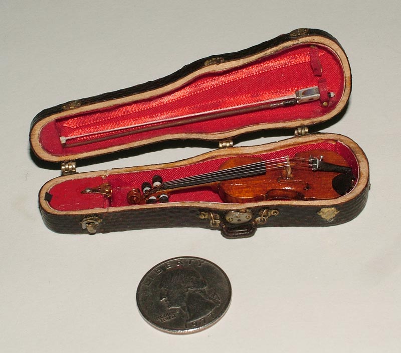 A miniature violin and bow in a fitted case, along with spare parts.