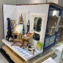 This small dollhouse room represents an artist’s studio on the inside with an ocean-themed blue front porch.